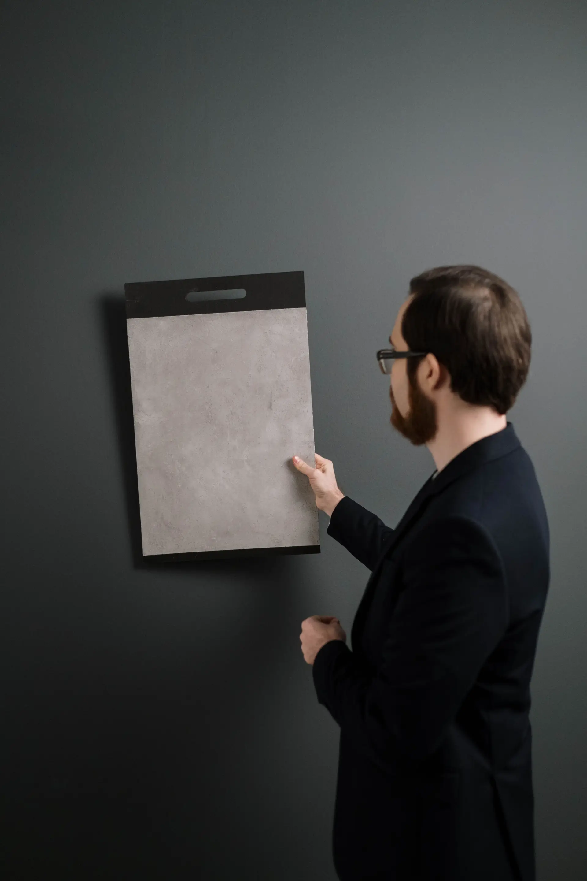 Architect examining detailed wall texture and architectural sample indoors