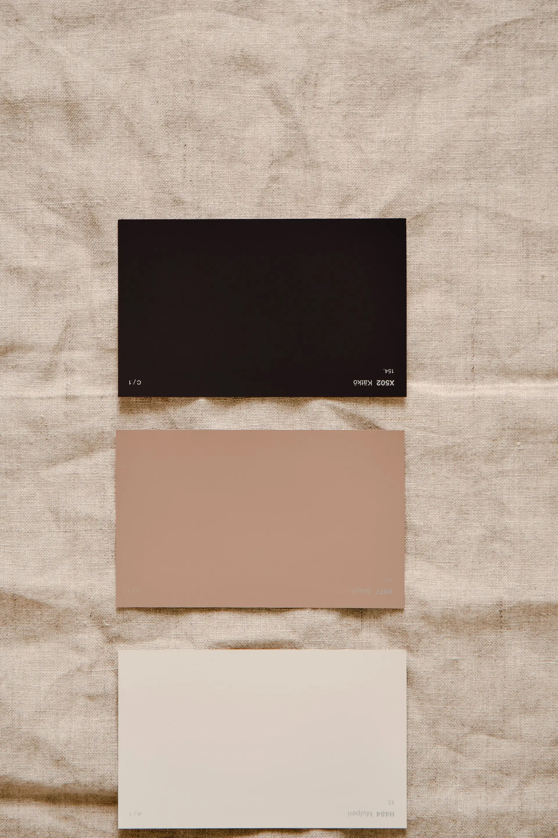 Interior designer color swatch cards resting on natural woven linen